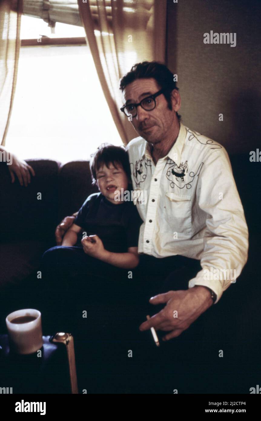 Ernest Watkins relaxes in the living room of the family's new home with son. Coffee and soft drinks have replaced Watkin's former habit of drinking beer on the weekends  ca.  1975 Stock Photo