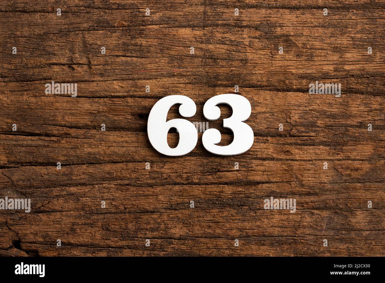 Number 63 - piece on rustic wood background Stock Photo - Alamy