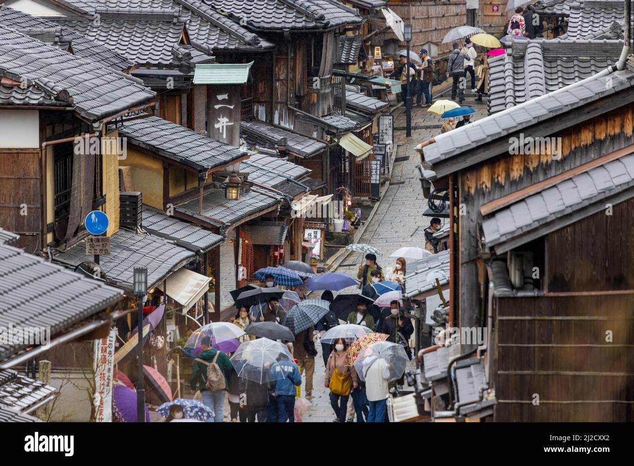 Overhead view of small crowd of people moving through history Kyoto district on rainy day Stock Photo