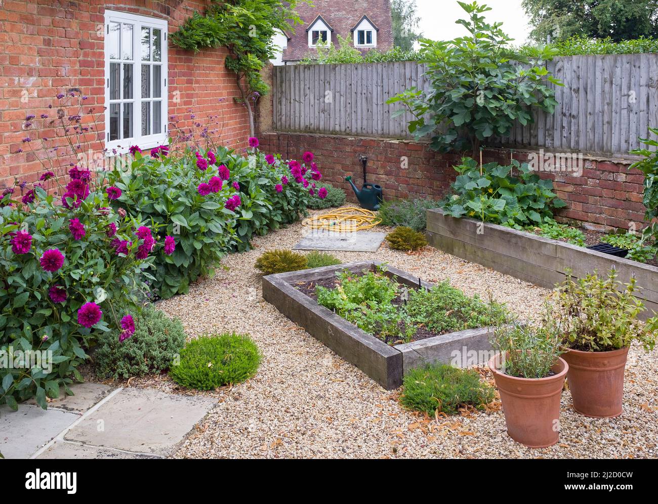 English cottage garden with gravel, UK. York stone paving and oak sleeper raised beds Stock Photo