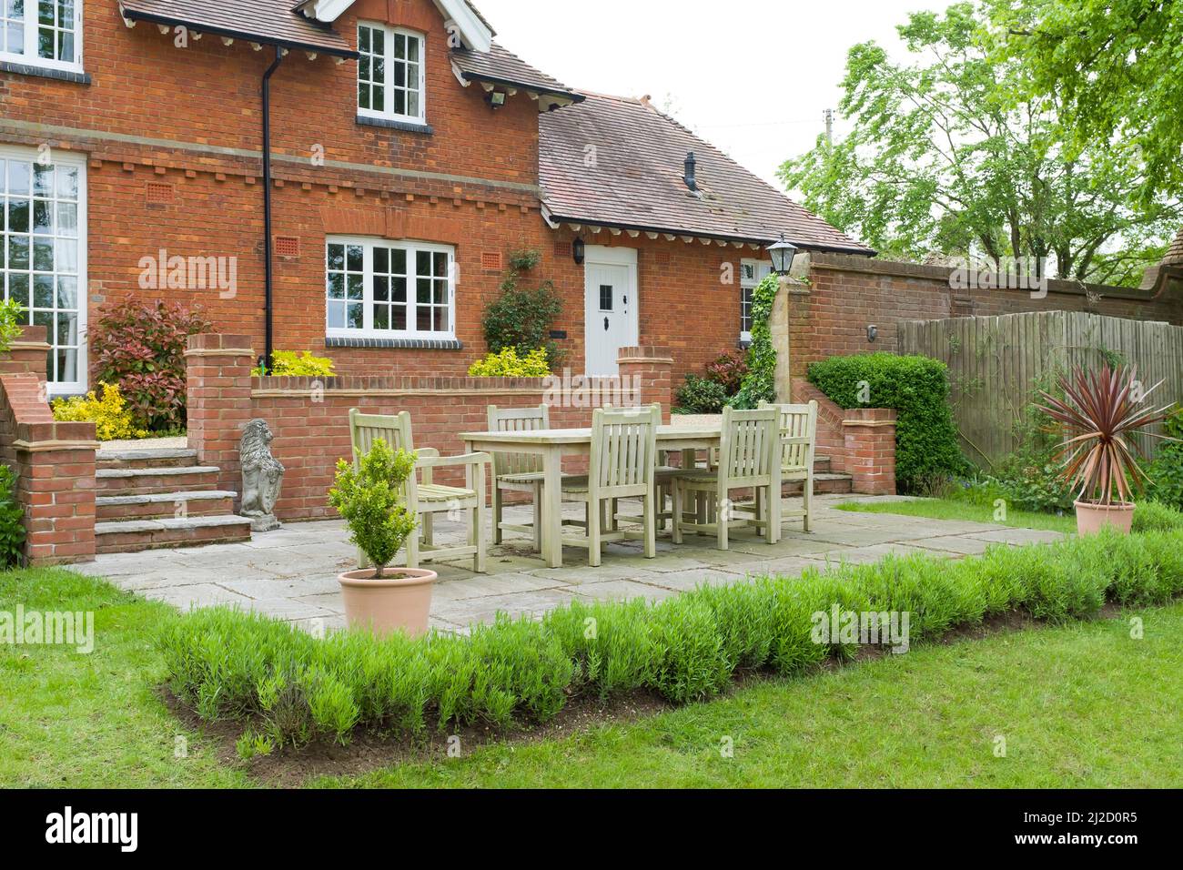 Large country home or house, with back garden, patio and wooden furniture. UK landscaped, terraced garden design Stock Photo