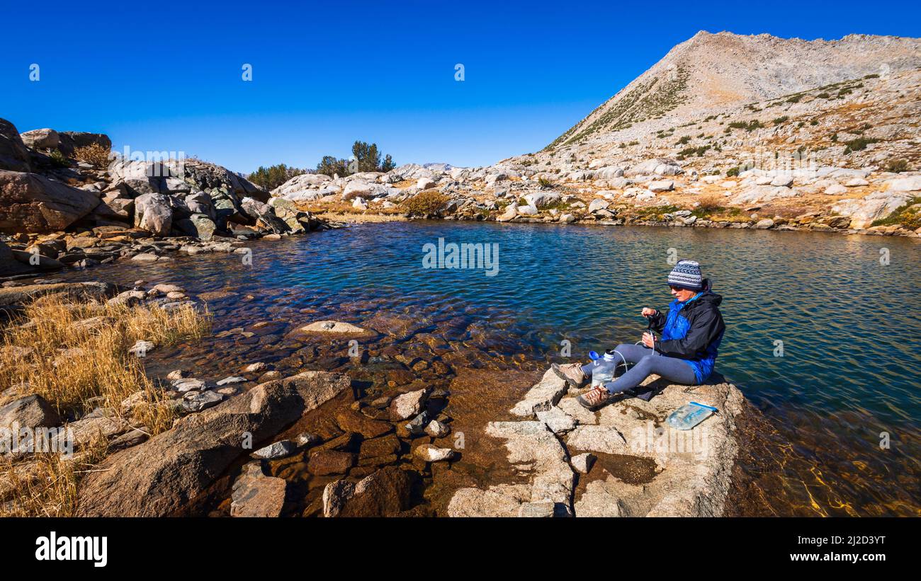 Backpacker purifying water in Dusy Basin, Kings Canyon National Park, California USA Stock Photo