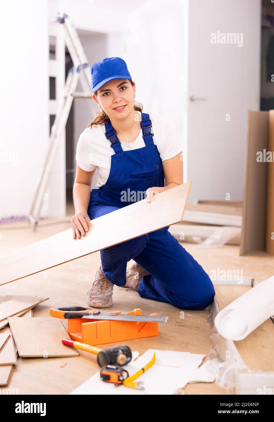 Woman construction worker setting wooden laminate board on floor Stock