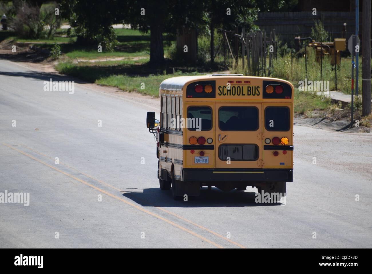 Short yellow school bus driving down a road in Rule Texas - August 2021 Stock Photo