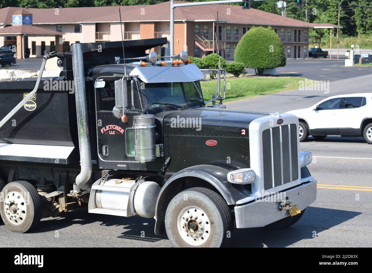 Black dump truck filled with broken slabs of concrete driving on a four
