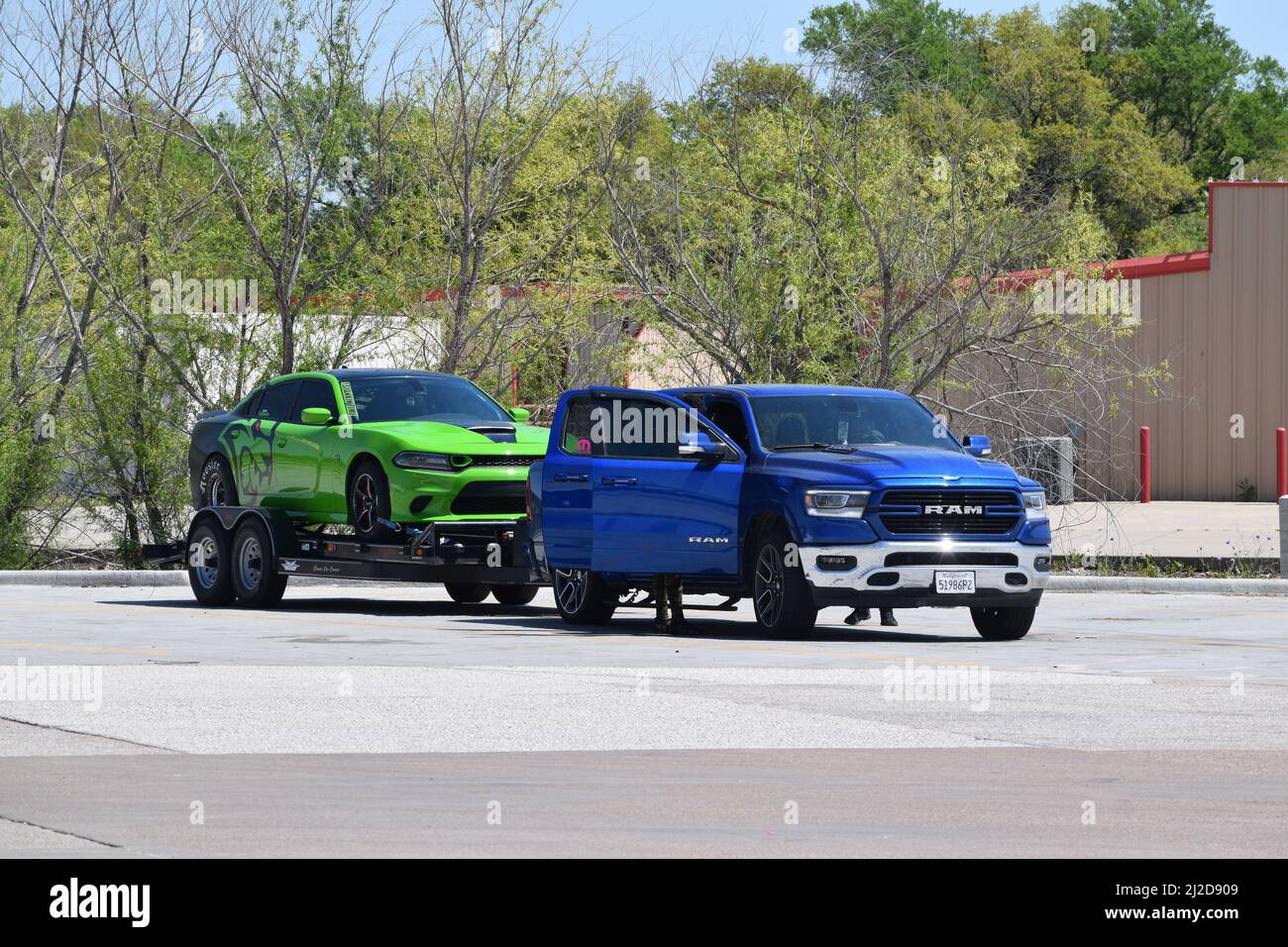 Blue Dodge Ram truck pulling a green Dodge Challenger Hellcat car on a trailer Stock Photo