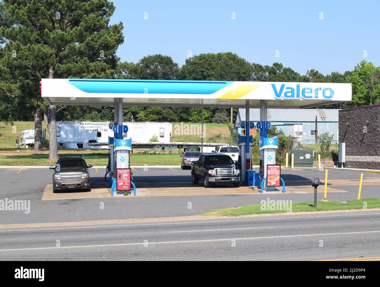 An SUV and pick up truck parked under the awning of a Valero gas station in Rockport, Arkansas Stock Photo