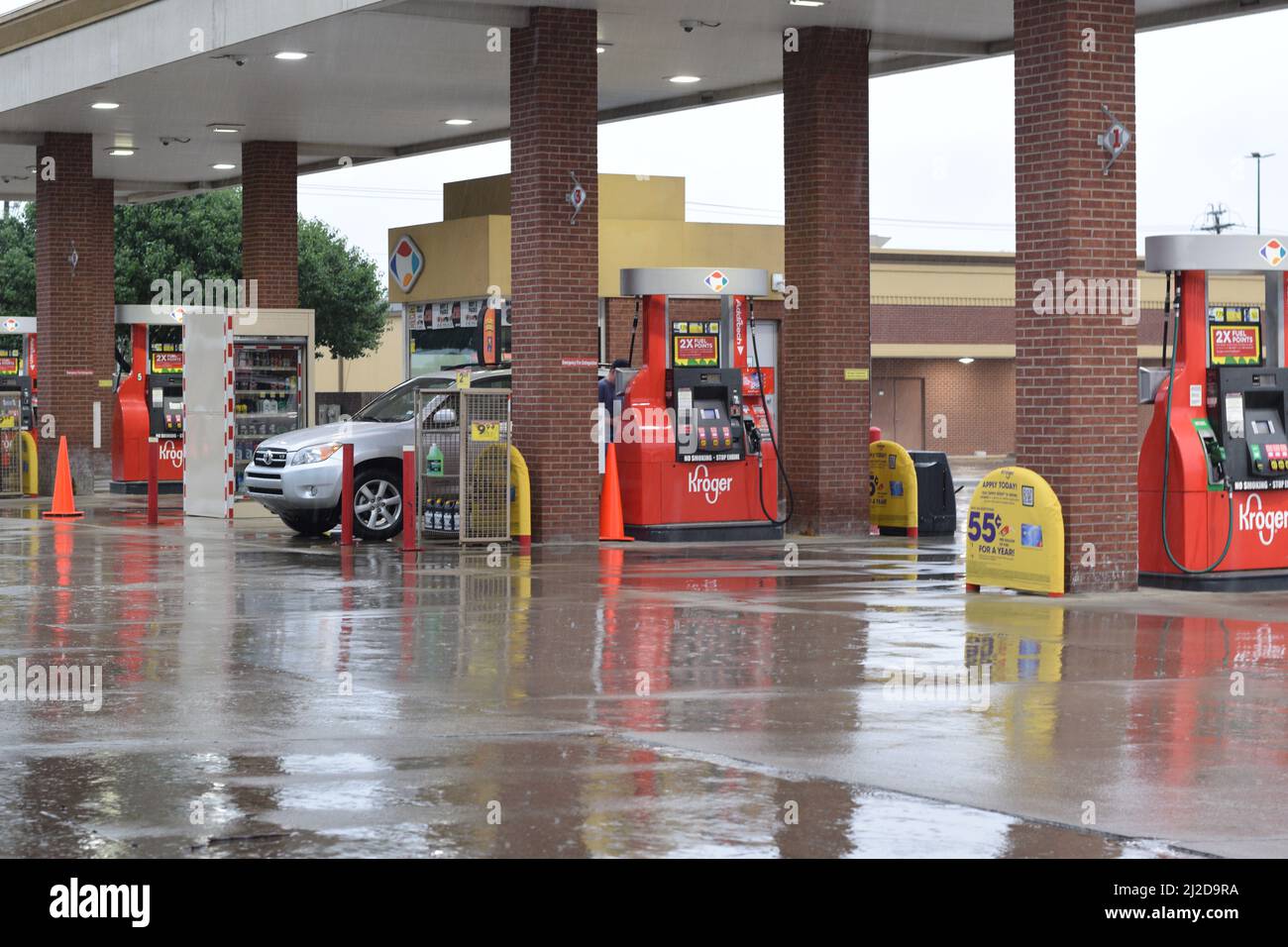 A customer pumps gas into his car at a Kroger gas station on a rainy day Stock Photo