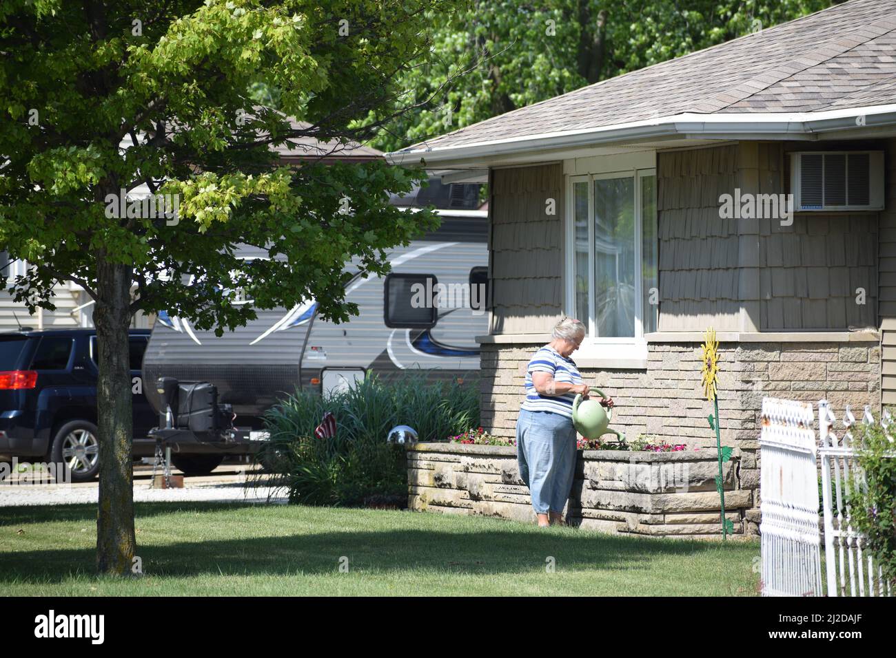 A woman in Cissna Park, IL (a small town in east central Illinois) using a watering can to water flowers Stock Photo