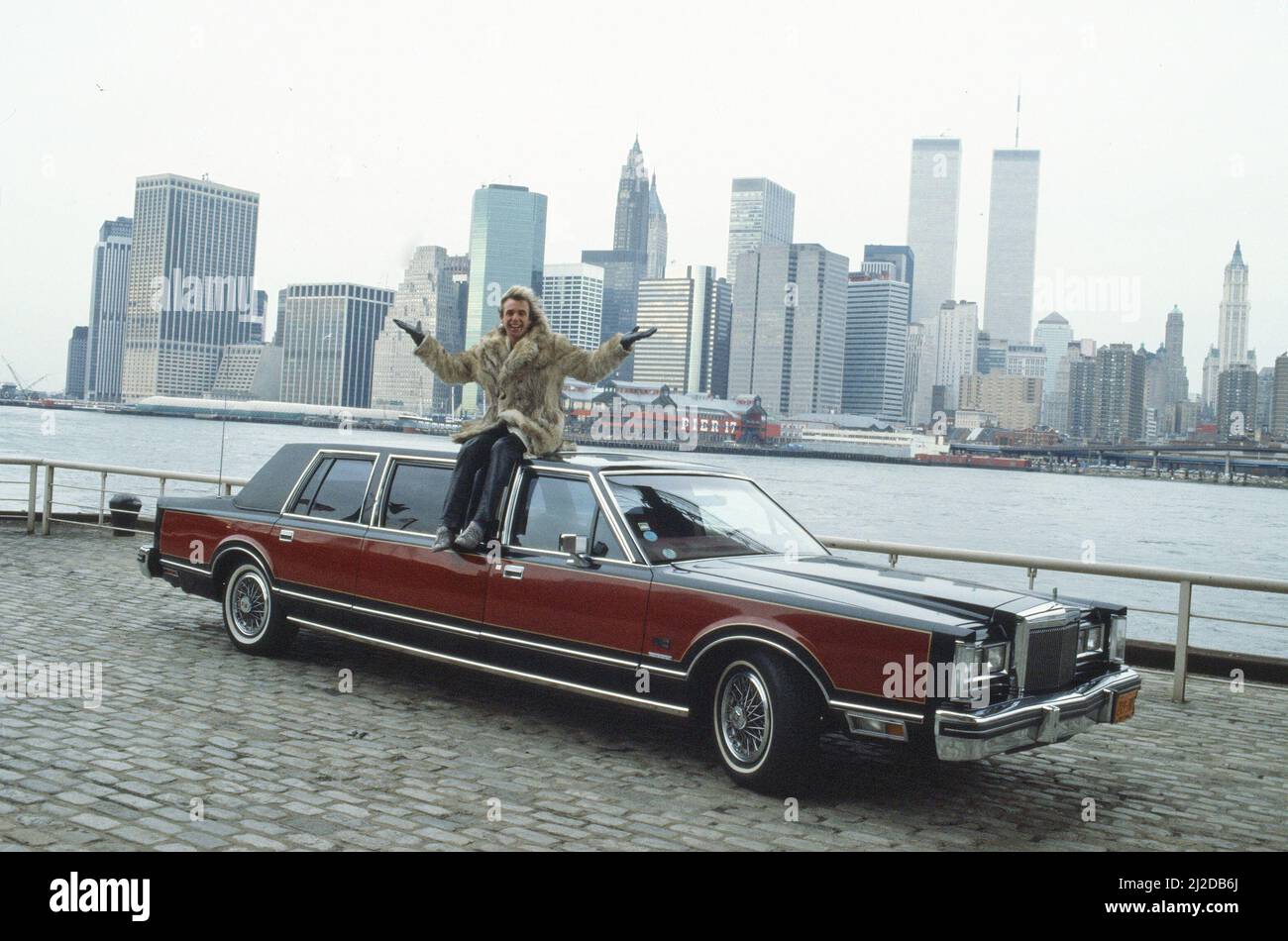 Peter Stringfellow, nightclub owner pictured in New York in January 1986, where Peter is opening Stringfellows New York.  He is sitting on a 45,000 dollar Lincoln Continental car with the Twin Towers of New York Manhattan in the background, 14th January 1986 Stock Photo