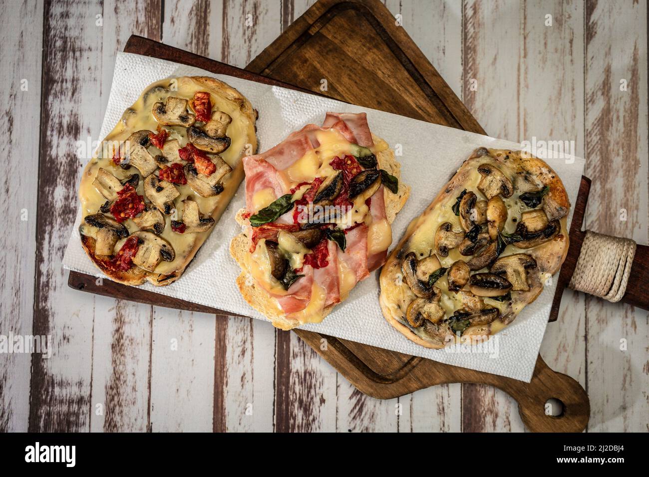 Large bruschettas with cheese, mushrooms, prosciutto and tomato in different combinations. Mediterranean food concept. top view Stock Photo
