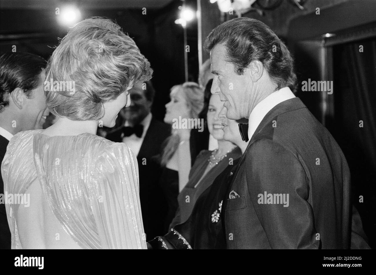 HRH The Princess of Wales, Princess Diana talking with lead actor Roger Moore at The Royal Premiere of the 14th 007 James Bond Movie, 'A View To A Kill'  at the Odeon Cinema, Leicester Square, London. This was Roger Moore's last of seven Bond Films. His first 'Live and Let Die', was released in 1973.  Princess Diana wears a stunning silver Bruce Oldfield dress.   In the background is actor Patrick Macnee, who plays Sir Godfrey Tibbett in the film.  Picture taken 14th June 1985 Stock Photo