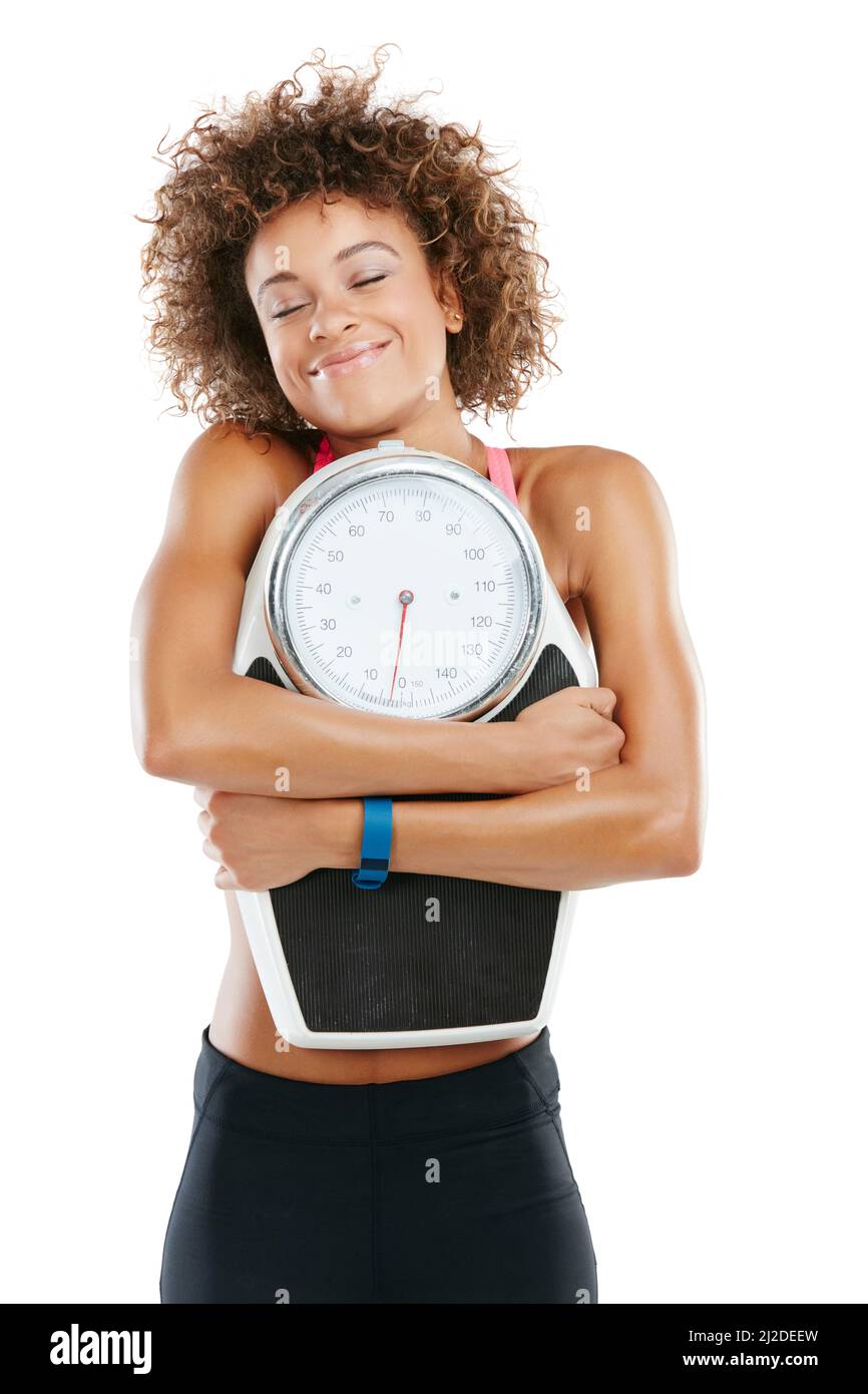 It feels great to be in shape. Studio shot of a fit young woman embracing a scale against a white background. Stock Photo