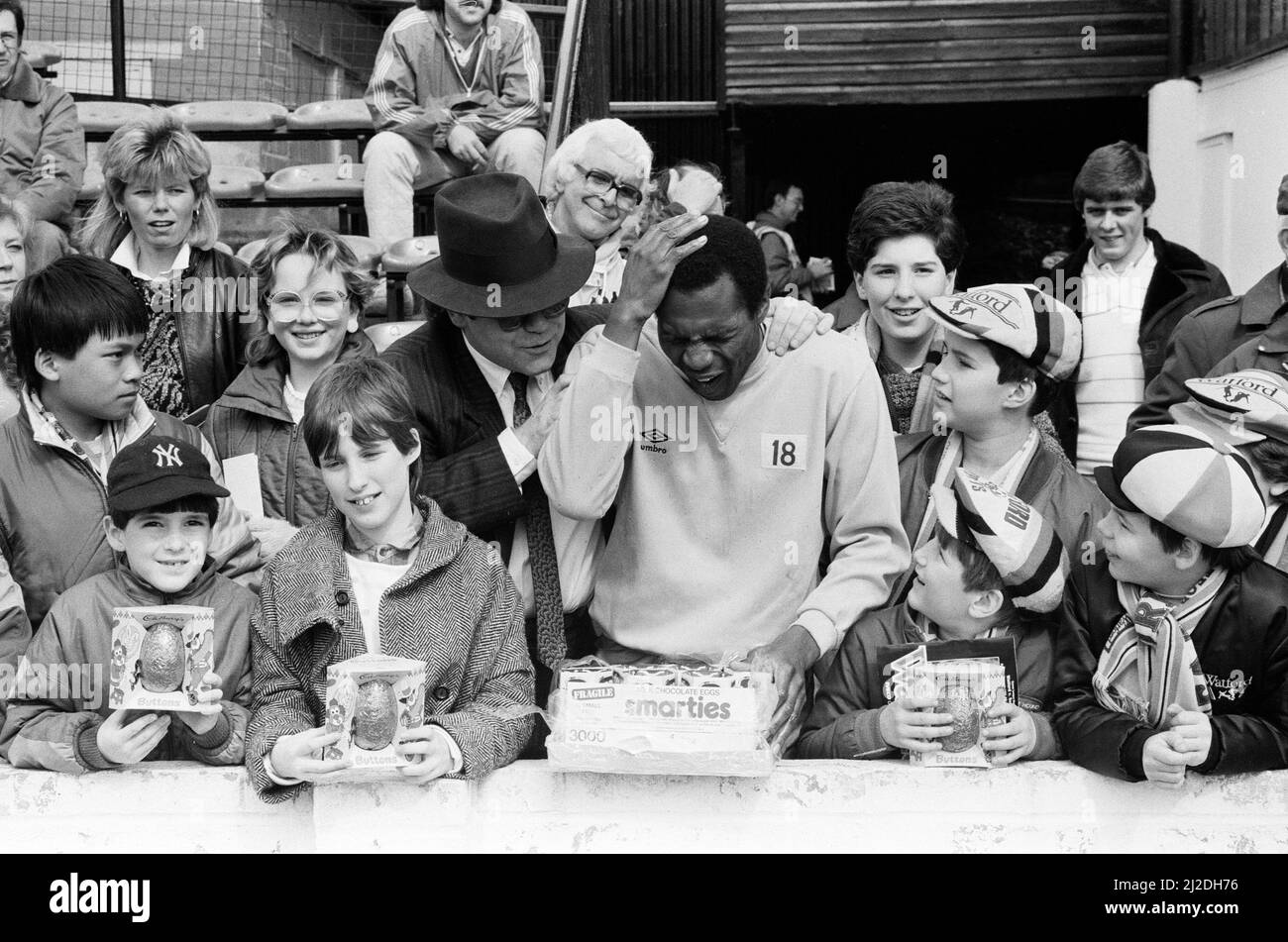 Pop star and Watford FC Chairman, Elton John, handing out Easter eggs to fans and clowning around with Luther Blissett. Watford v Southampton football match. 6th April 1985. Stock Photo