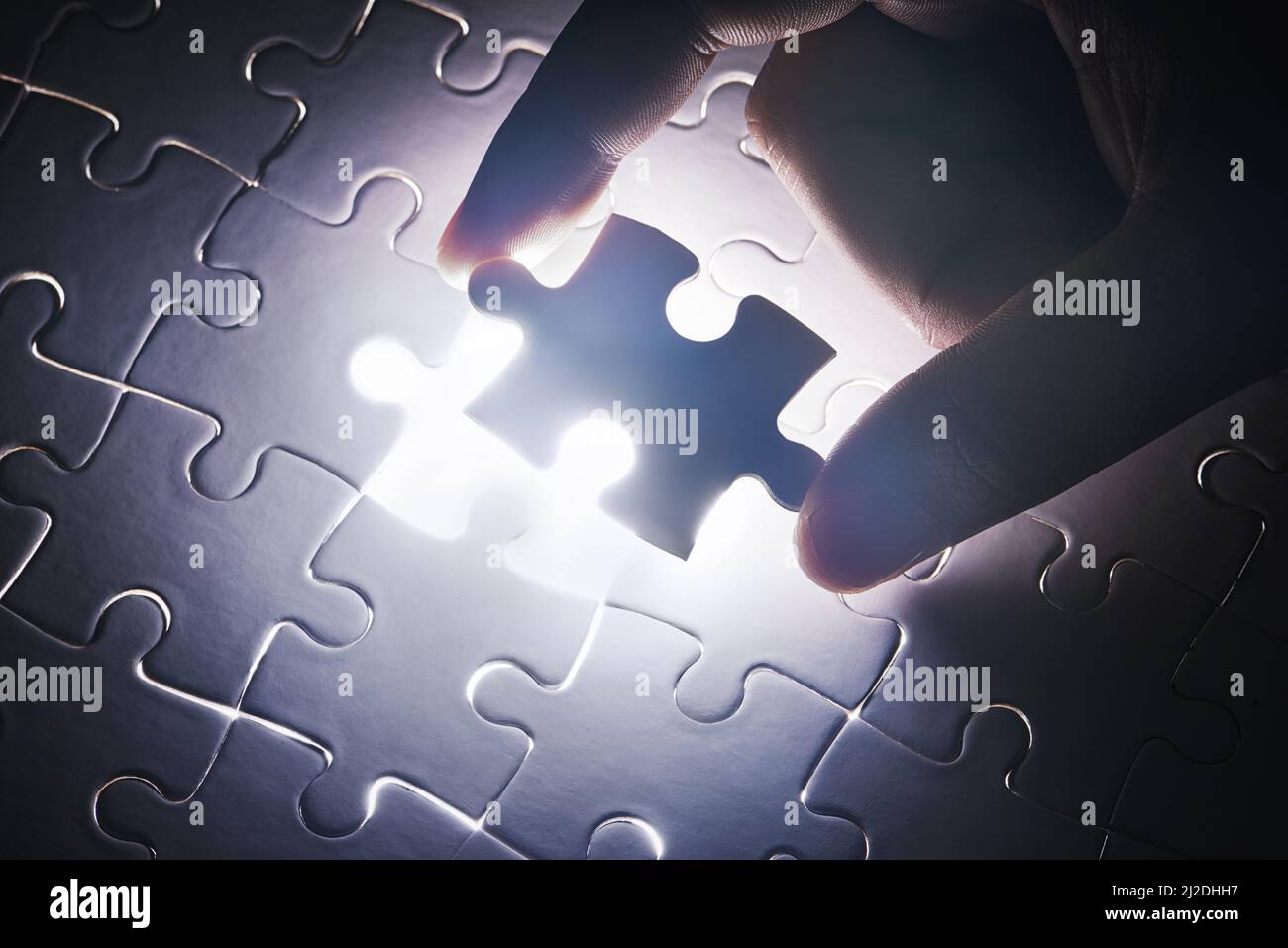 The last piece to place. Conceptual shot of a persons hand building a puzzle. Stock Photo