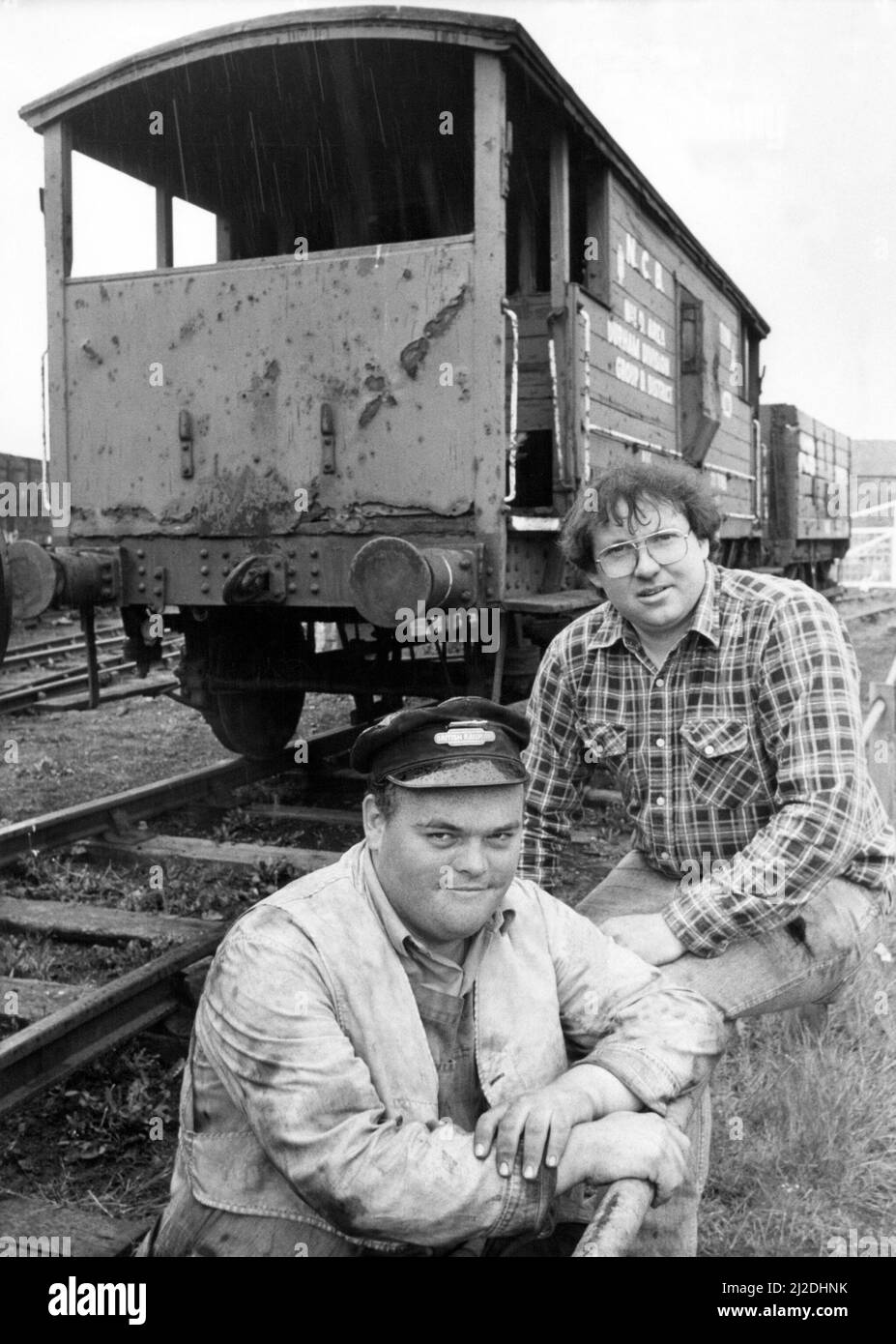 Malcolm Brown left, and Gordon Bainbridge, beside a fire damaged guards van and hopper on 30th June 1985 Stock Photo