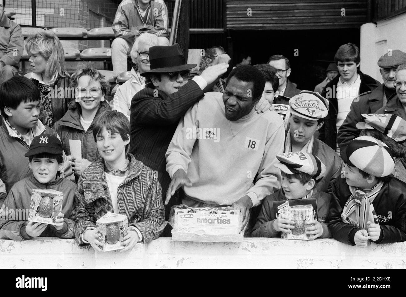 Pop star and Watford FC Chairman, Elton John, handing out Easter eggs to fans and clowning around with Luther Blissett. Watford v Southampton football match. 6th April 1985. Stock Photo