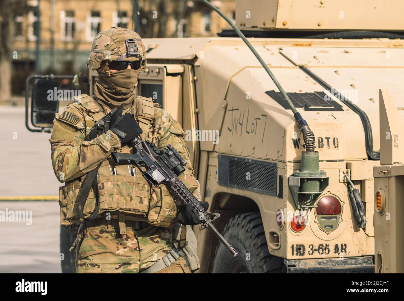United States - March 29 2022: United States Marine Corps soldier with covered face and sunglasses, shotgun and armored vehicle humvee in the city, US Stock Photo