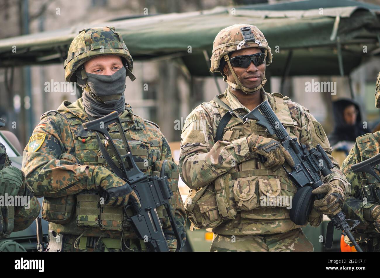 NATO soldier with sunglasses, shotgun or rifle and armored vehicle humvee, USA or US army troops ready for war Stock Photo