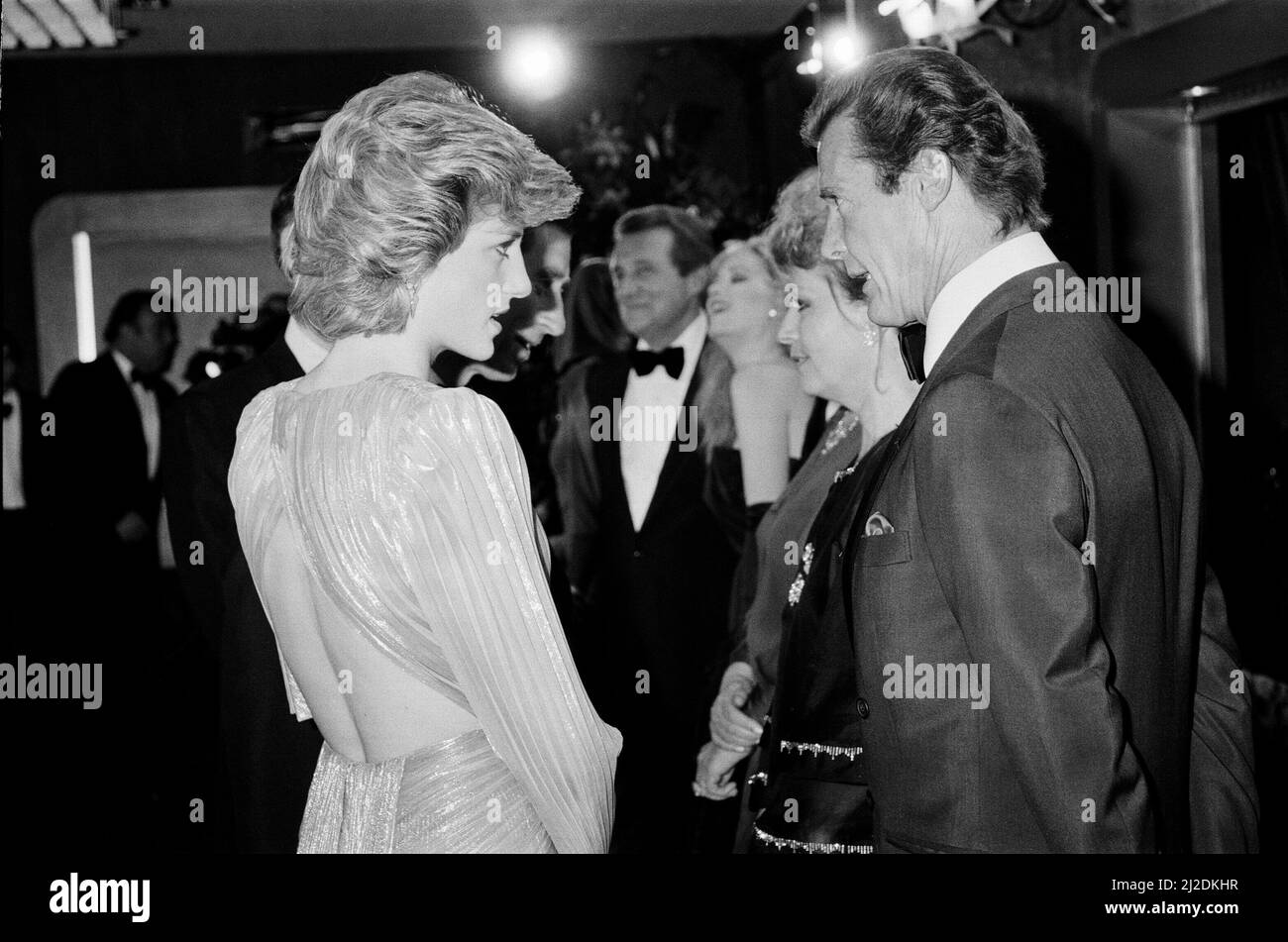 HRH The Princess of Wales, Princess Diana talking with lead actor Roger Moore at The Royal Premiere of the 14th 007 James Bond Movie, 'A View To A Kill'  at the Odeon Cinema, Leicester Square, London. This was Roger Moore's last of seven Bond Films. His first 'Live and Let Die', was released in 1973.  Princess Diana wears a stunning silver Bruce Oldfield dress.   In the background is actor Patrick Macnee, who plays Sir Godfrey Tibbett in the film.  Picture taken 14th June 1985 Stock Photo