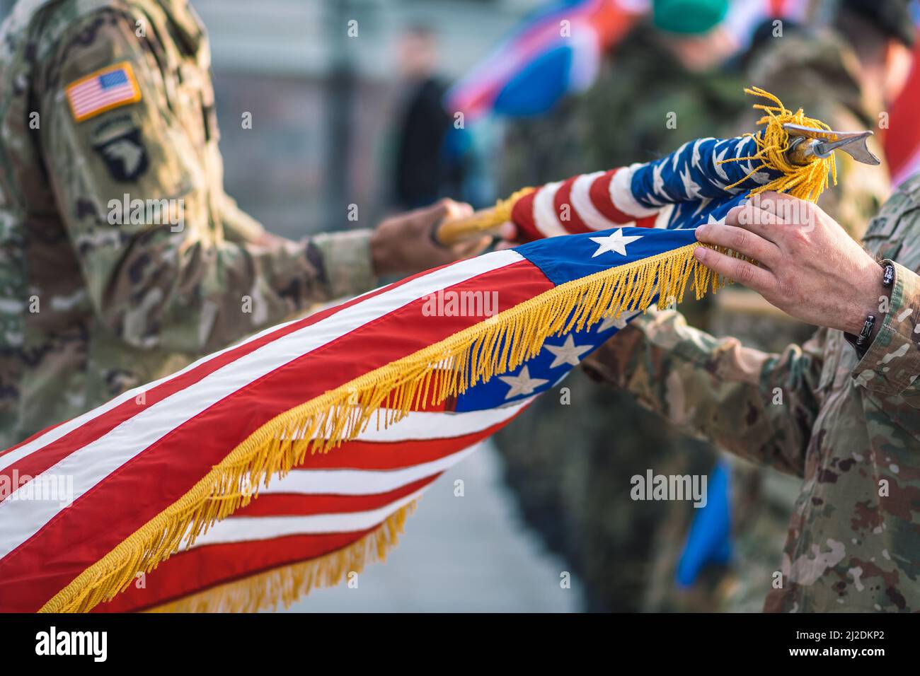 United States Marine Corps soldiers roll up American flag, USA or US army troops ready for drills or war Stock Photo