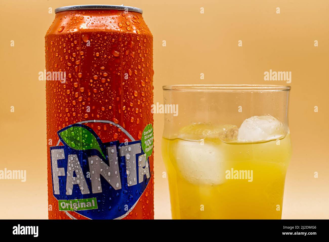 Bologna - Italy - November 17, 2020: Can of Fanta soda, glass and ice isolated on yellow background Stock Photo