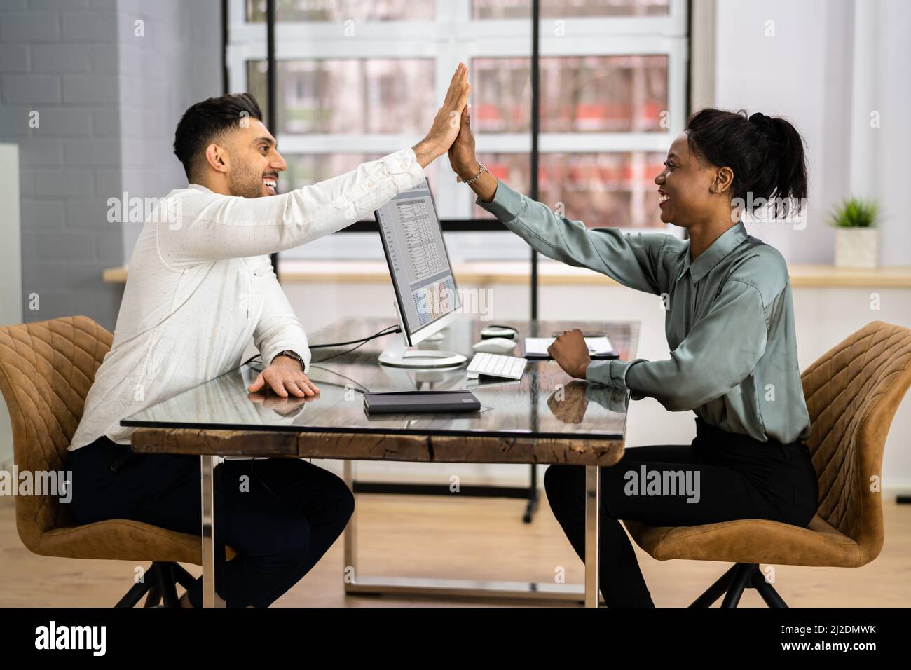 Businessman And Businesswoman Sitting On Chair Giving High Five In ...