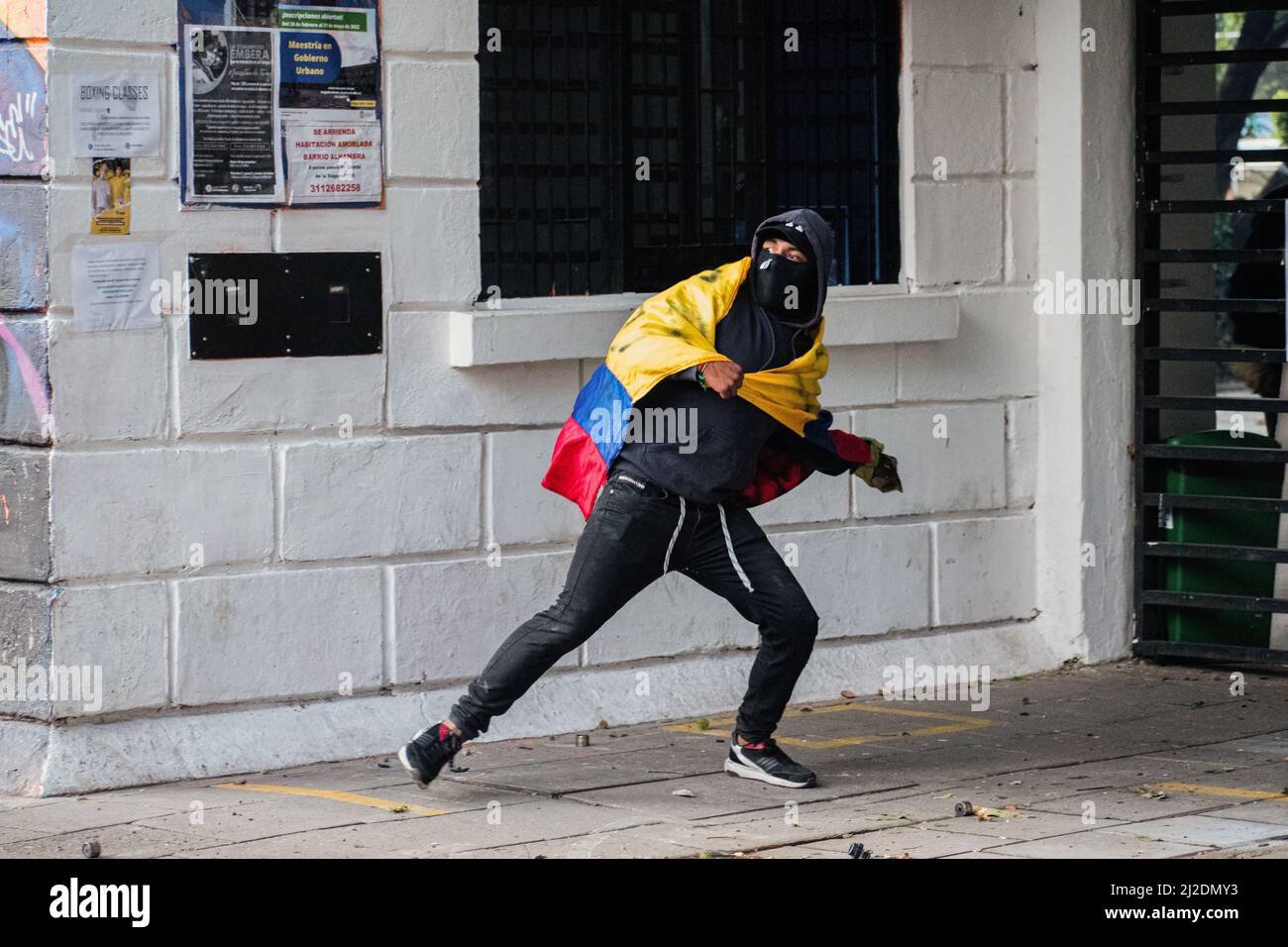 A demonstrator uses a Colombian flag while throwing rocks and debree as students protested against Colombia's national police and government on March 31, 2022 in Bogota, Colombia. As demonstrators and Colombia's riot police squad 'ESMAD' ended up in clashes in northern Bogota. Photo by: Daniel Romero/Long Visual Press Stock Photo