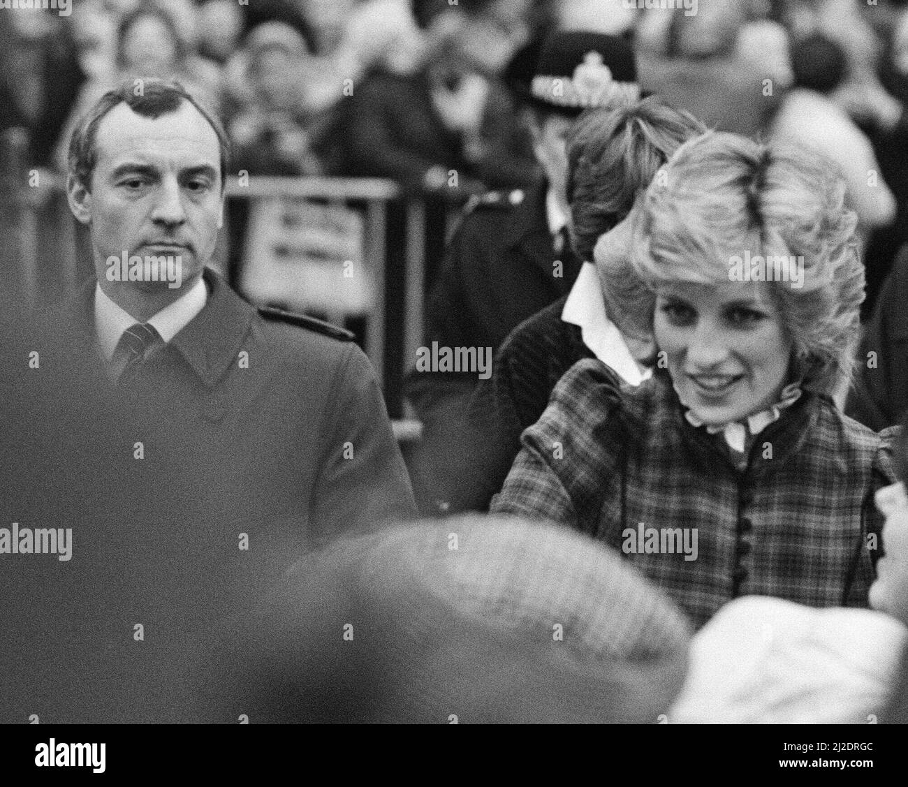 **this is a crop from the fuller wide frame** The Prince and Princess of Wales visit Mid Glamorgan in Wales. On this visit, they meet the local well-wishers outside a newly electronics plant.  Picture shows Princess Diana and behind her, her bodyguard Barry Mannakee wearing a diagonal striped tie and overcoat/mac.  See other frames in this set wear Mr Mannakee has taken this coat off and is wearing a slight pin striped suit.  Picture taken 29th January 1985 Stock Photo