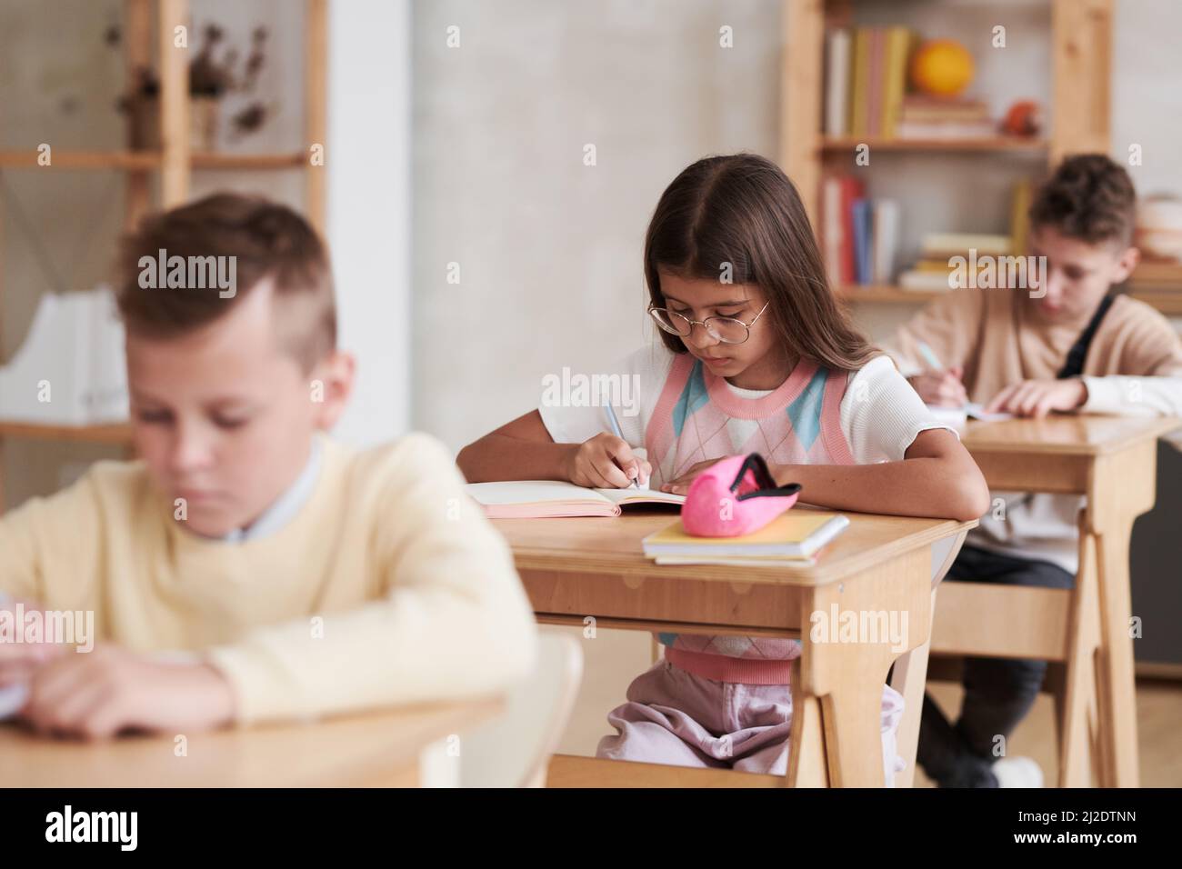 Group of children sitting at desks in row in school classroom, focus on