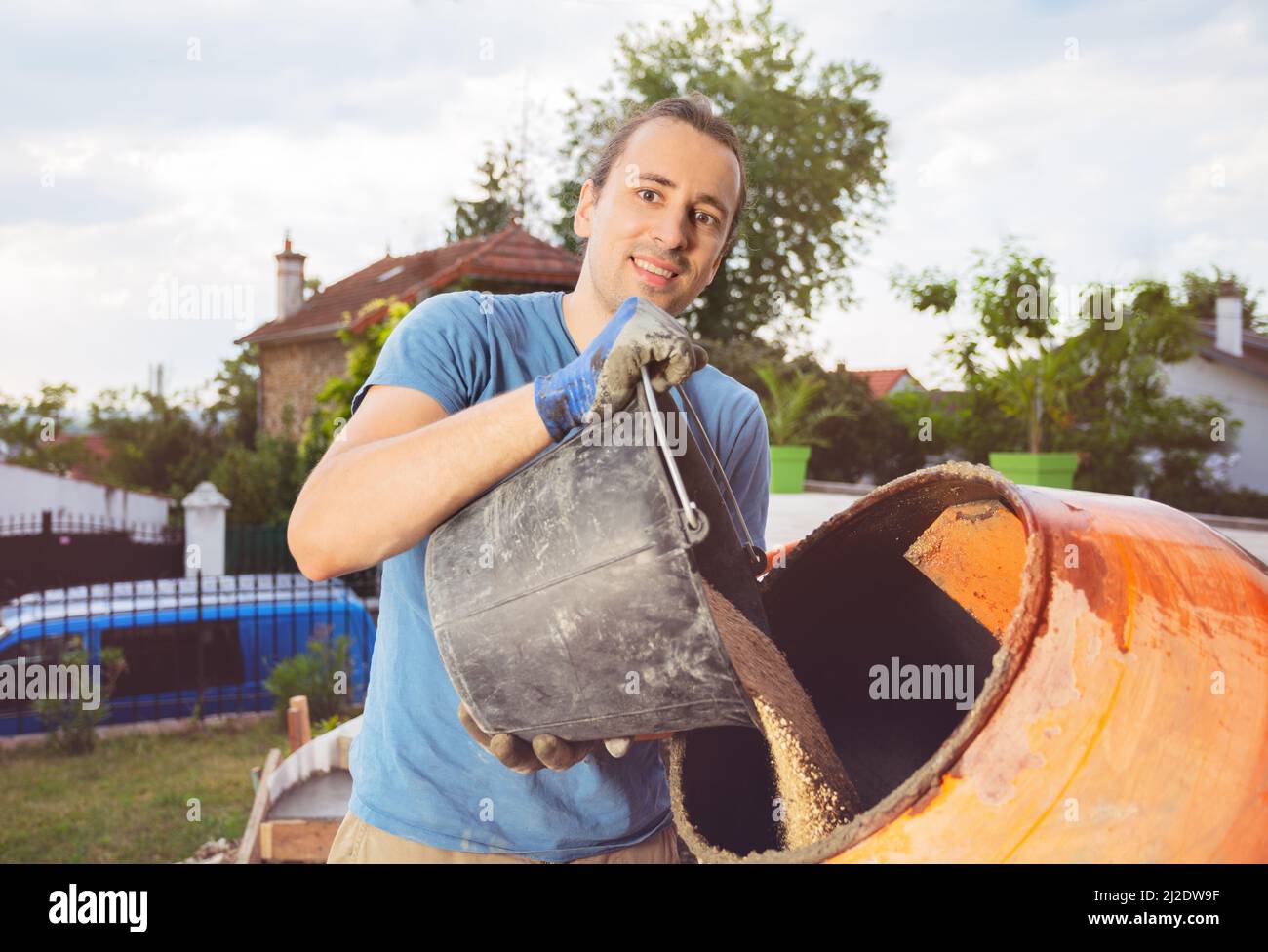 Man add a bucket of sand to cement mixer doing DIY work at home Stock Photo Alamy