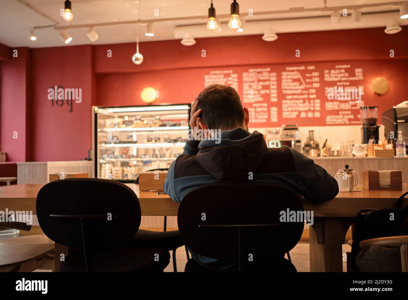 Worried busy man is sitting in cafe and working on complex project. Concept of ideas of lightbulbs over head. The chair is not comfortable, problems Stock Photo