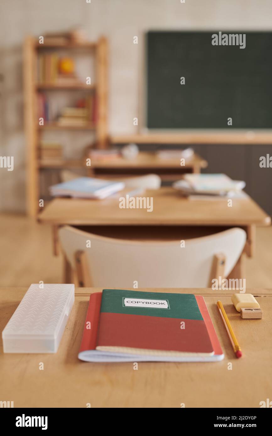 Vertical image of wooden school desks in row facing blackboard in empty