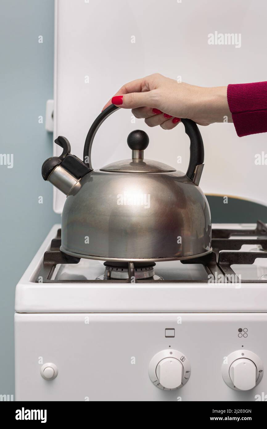 female hand puts a metal kettle on a gas burner. High quality photo