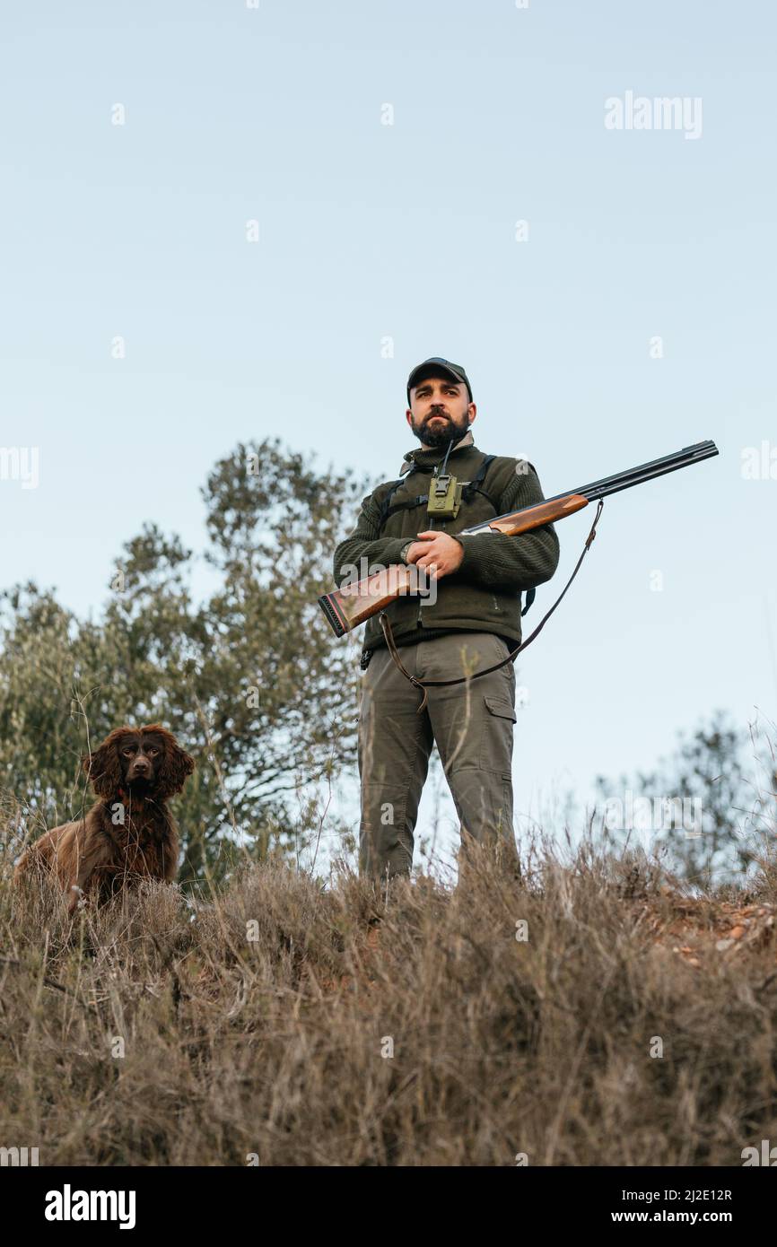 Portrait of man holding his shotgun with his dog next to him Stock Photo