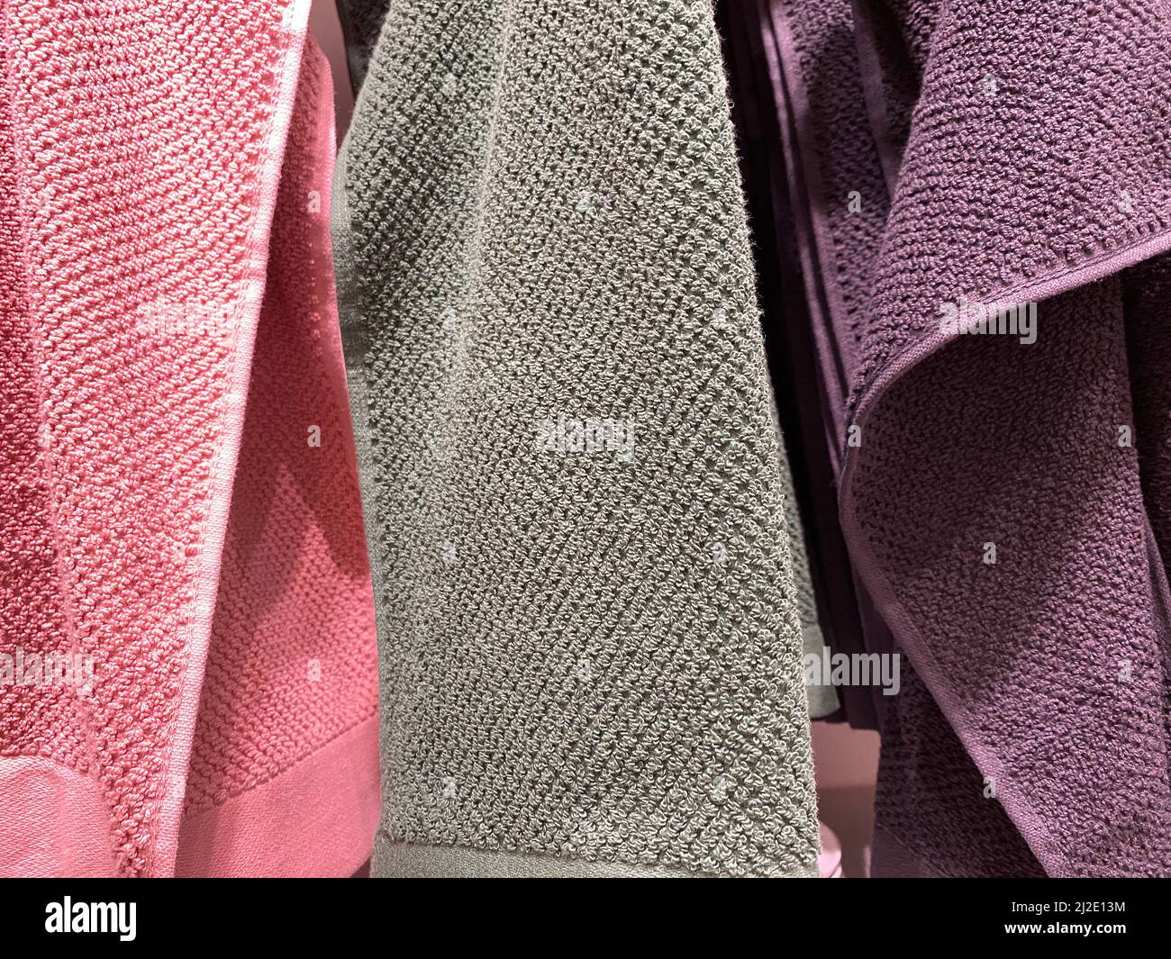 Bath Towels. Gray, pink, and purple cotton terry towels hang side by