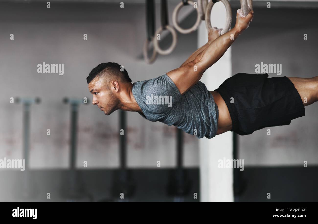 Pure power. Cropped shot of a young man working out on the gymnastics rings. Stock Photo