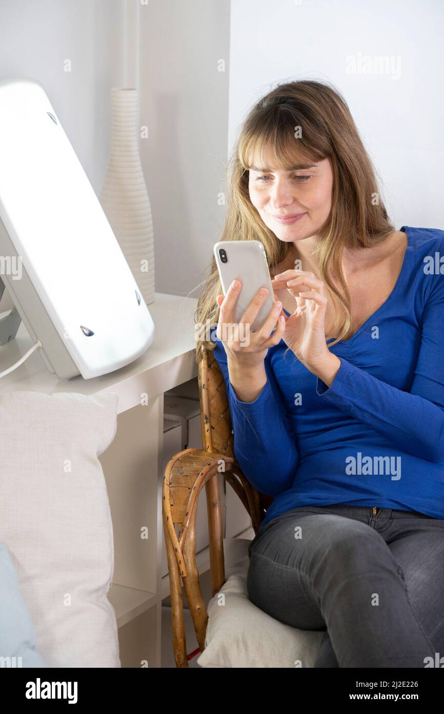 Woman smartphone light therapy Stock Photo