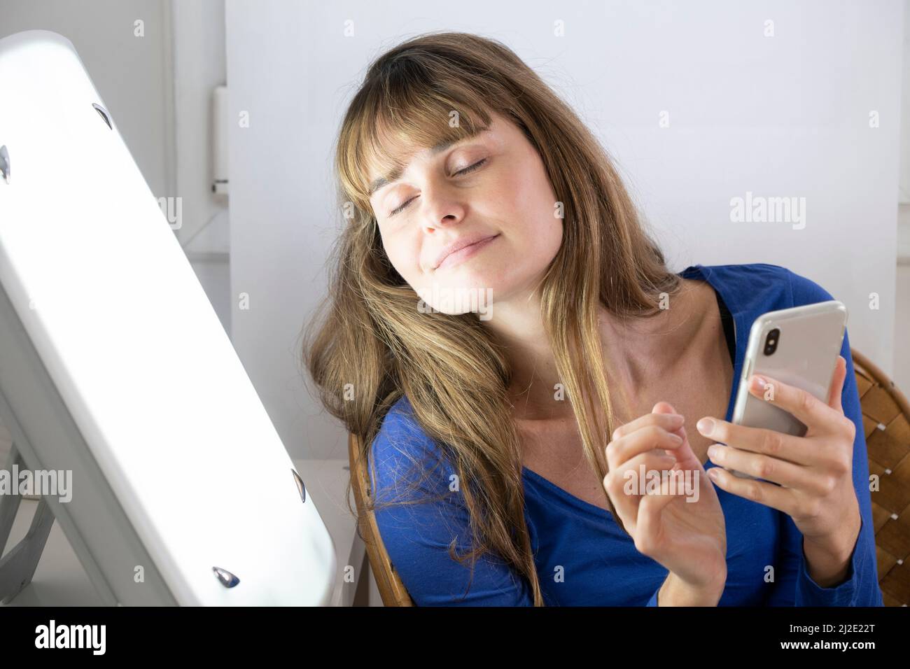 Woman smartphone light therapy Stock Photo