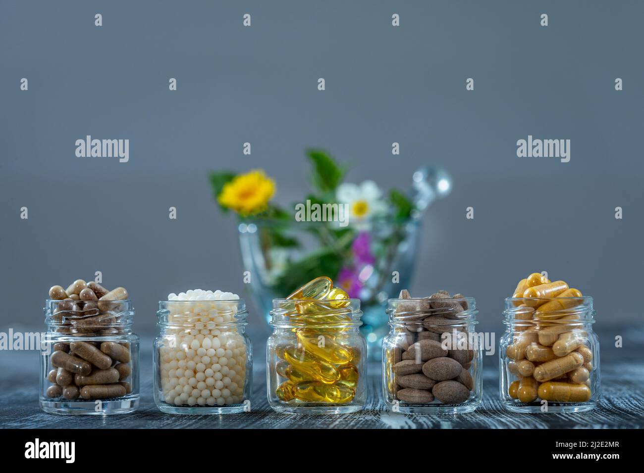Bottle of pills food suplements healthy medicine, medication health care treatment additives pharmacy with ceramic white mortar with medicinal fresh plants on background Stock Photo