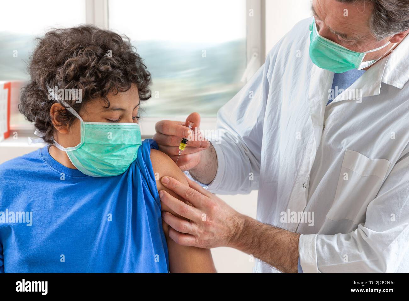 Male doctor in protective face mask latex gloves giving intramuscular vaccination protected patient's arm Stock Photo
