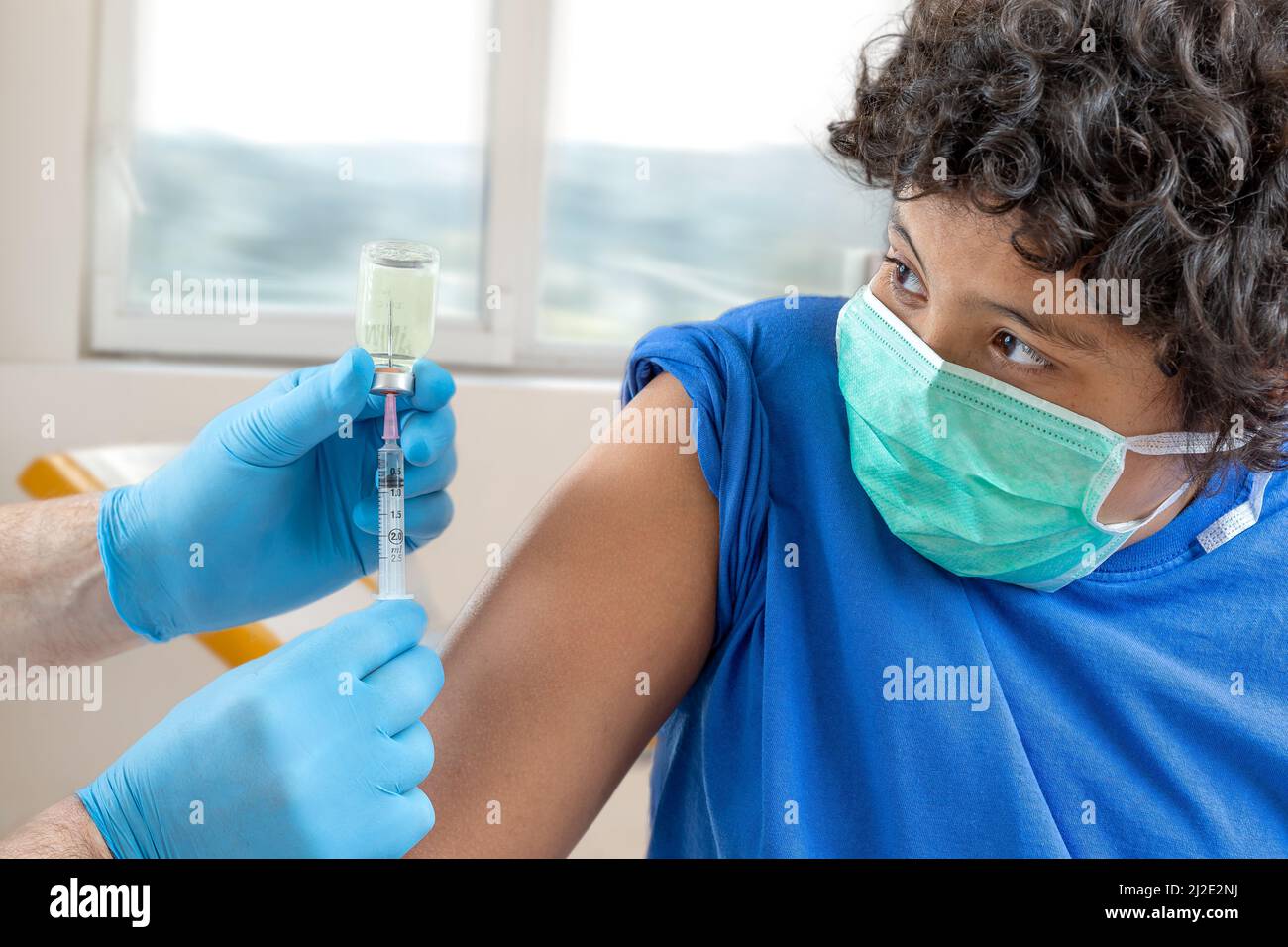 Male doctor in protective face mask latex gloves giving intramuscular vaccination protected patient's arm Stock Photo