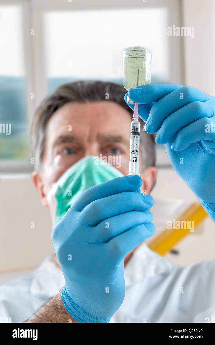 The doctor fills a syringe with vaccine on blurred background. Stock Photo