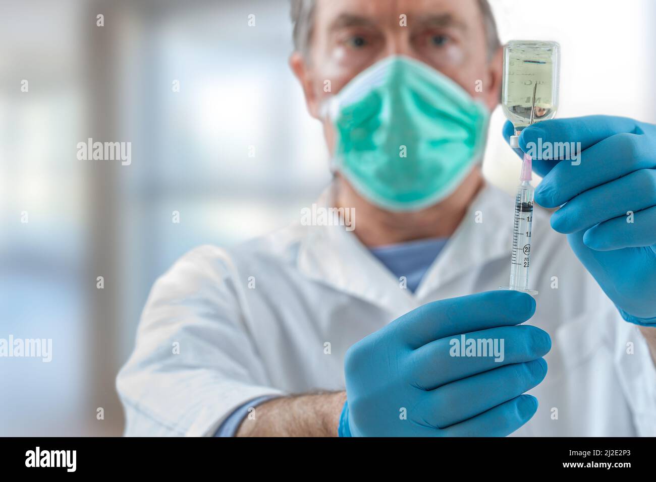 The doctor fills a syringe with vaccine on blurred background. Stock Photo