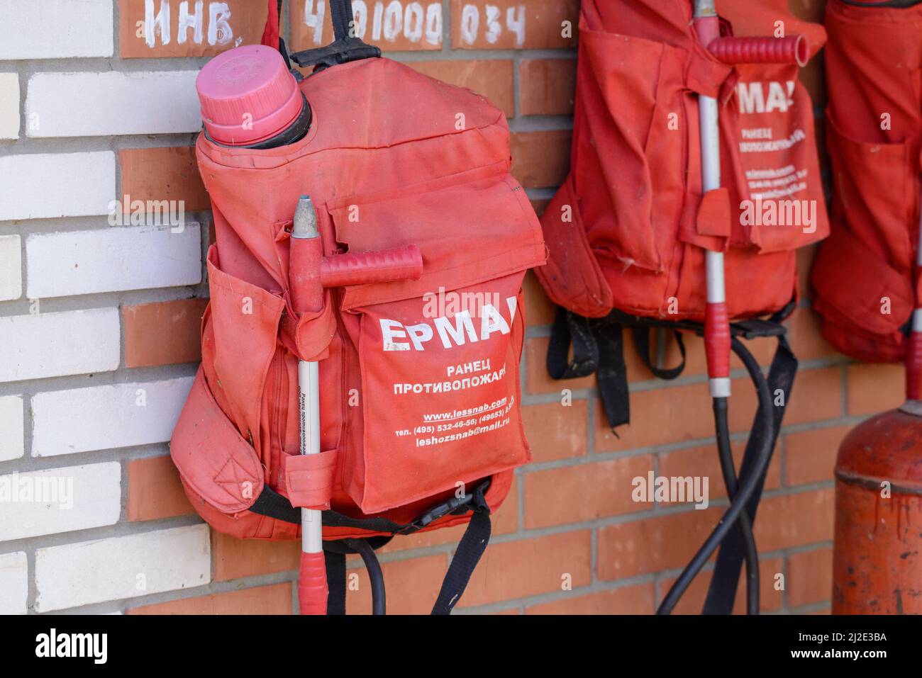 Russia, Rostovskaya oblast, 2021 September 01: Knapsack fire extinguishers on a wall. Sign on russian Ermak. Knapsack fire extinguisher. Stock Photo