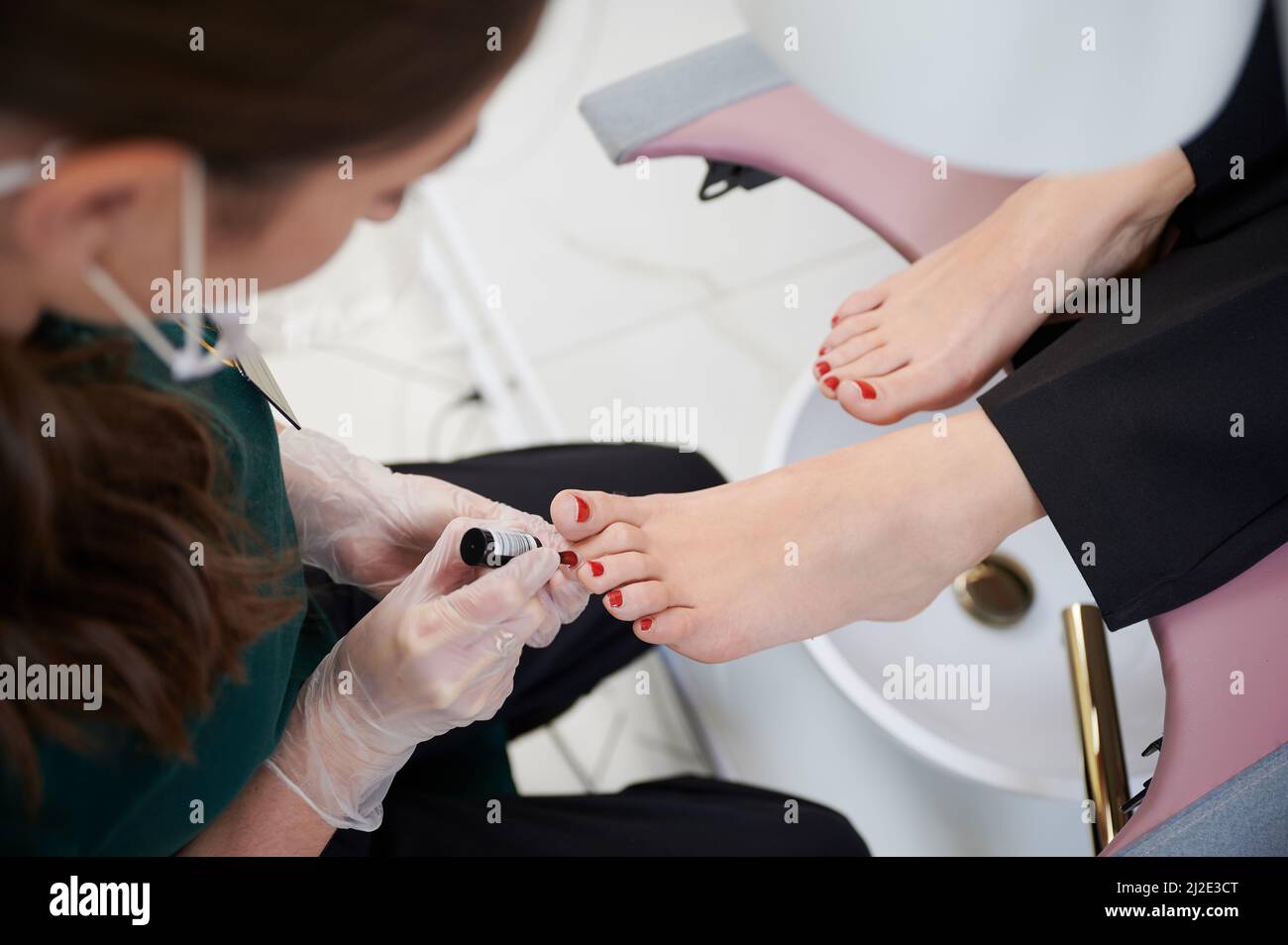 Nail specialist doing pedicure for client in beauty salon. Close up of