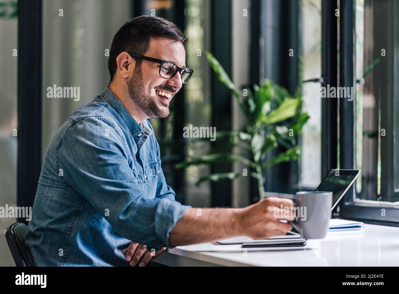 Joyful caucasian man, putting his drink down, getting back to work. Stock Photo