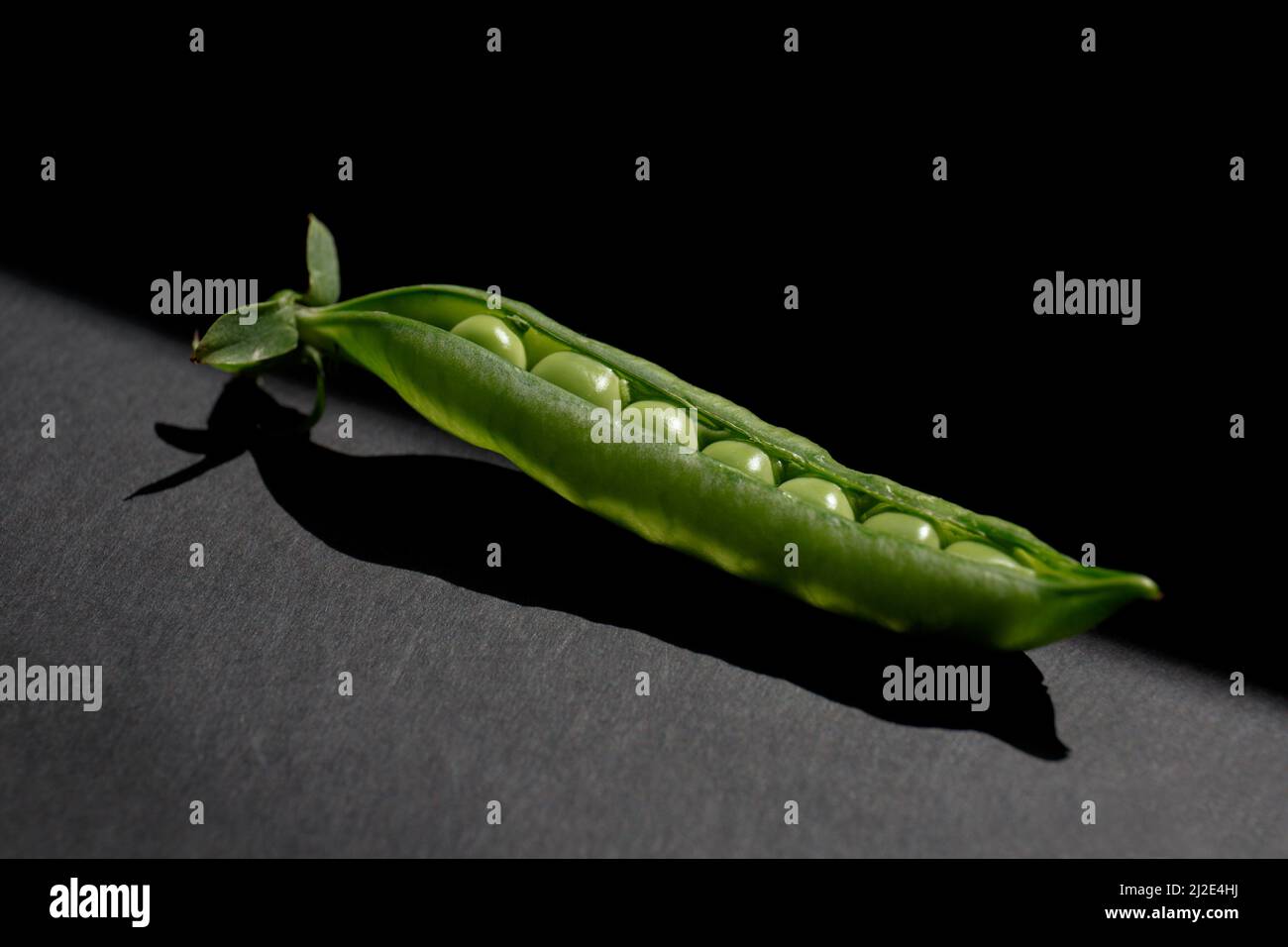 Pod of green peas on a black background. Pea grains in an open pod Stock Photo