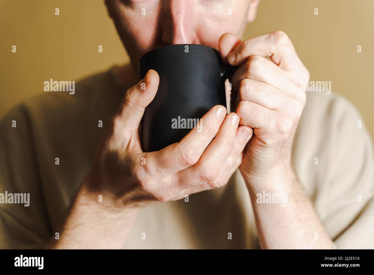 Portrait of a man drinking coffee from a black cup, White man drinking from a cup, close-up Stock Photo