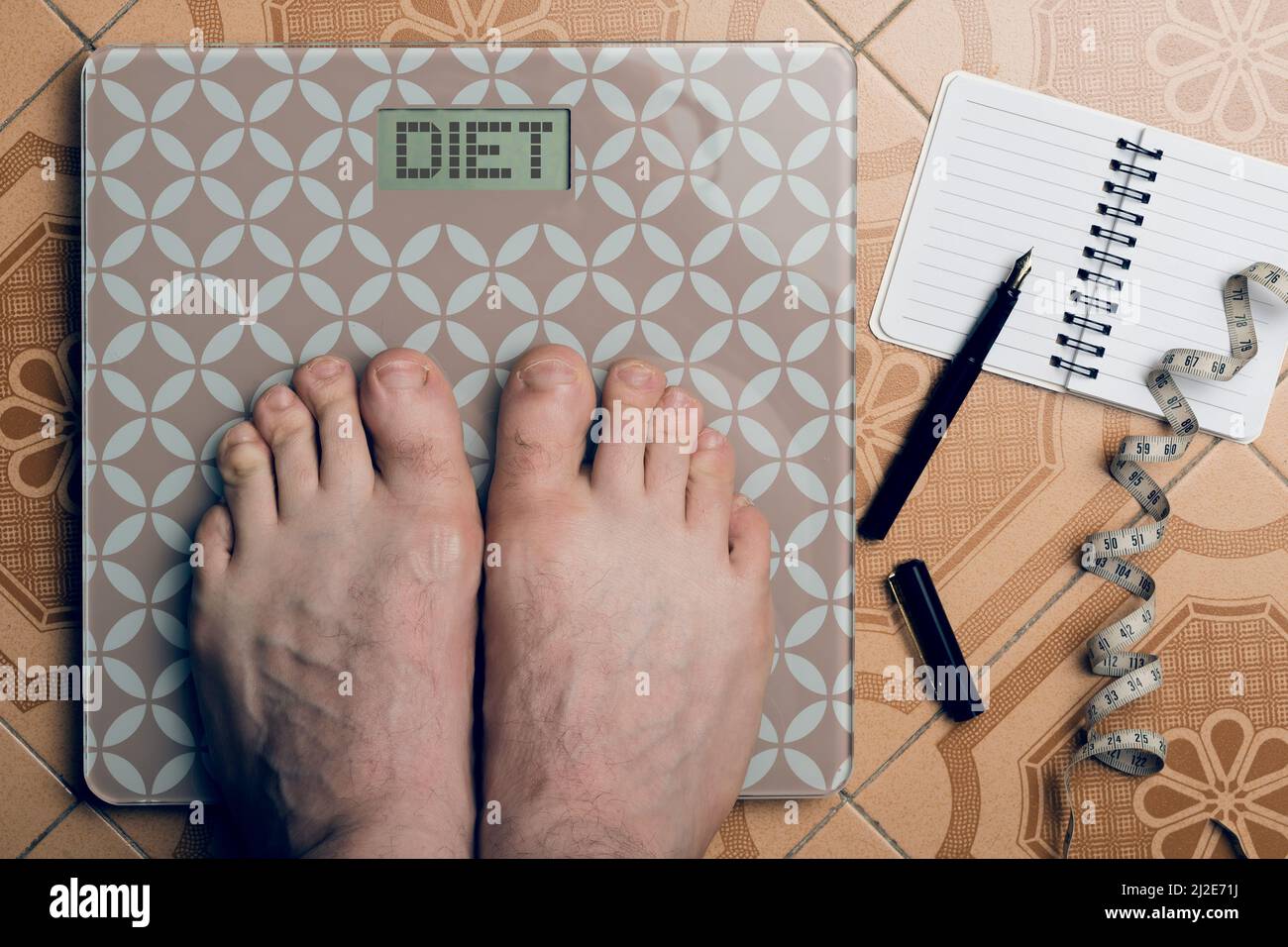 Weight loss concept, man with his feet on a scales showing the inscription: diet Stock Photo